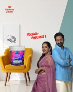 A Diamond Paints best interior paint ad showing a smiling man and woman next to a yellow chair holding a bucket of Diamond Shine bucket. Red Malayalam text 'സംഭവം കളറാണ്!' is in the center.